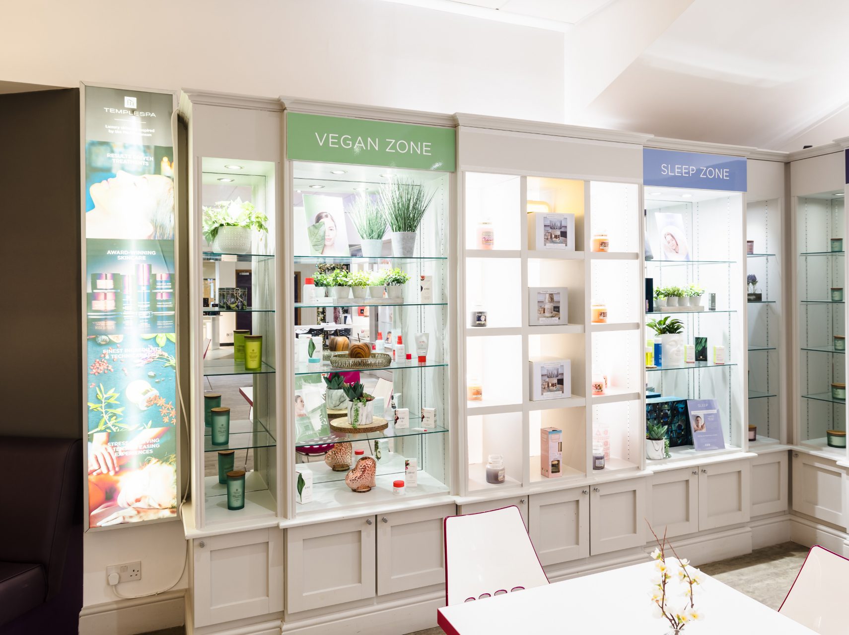 A well-lit display of skincare and beauty products on shelves, featuring labeled sections 