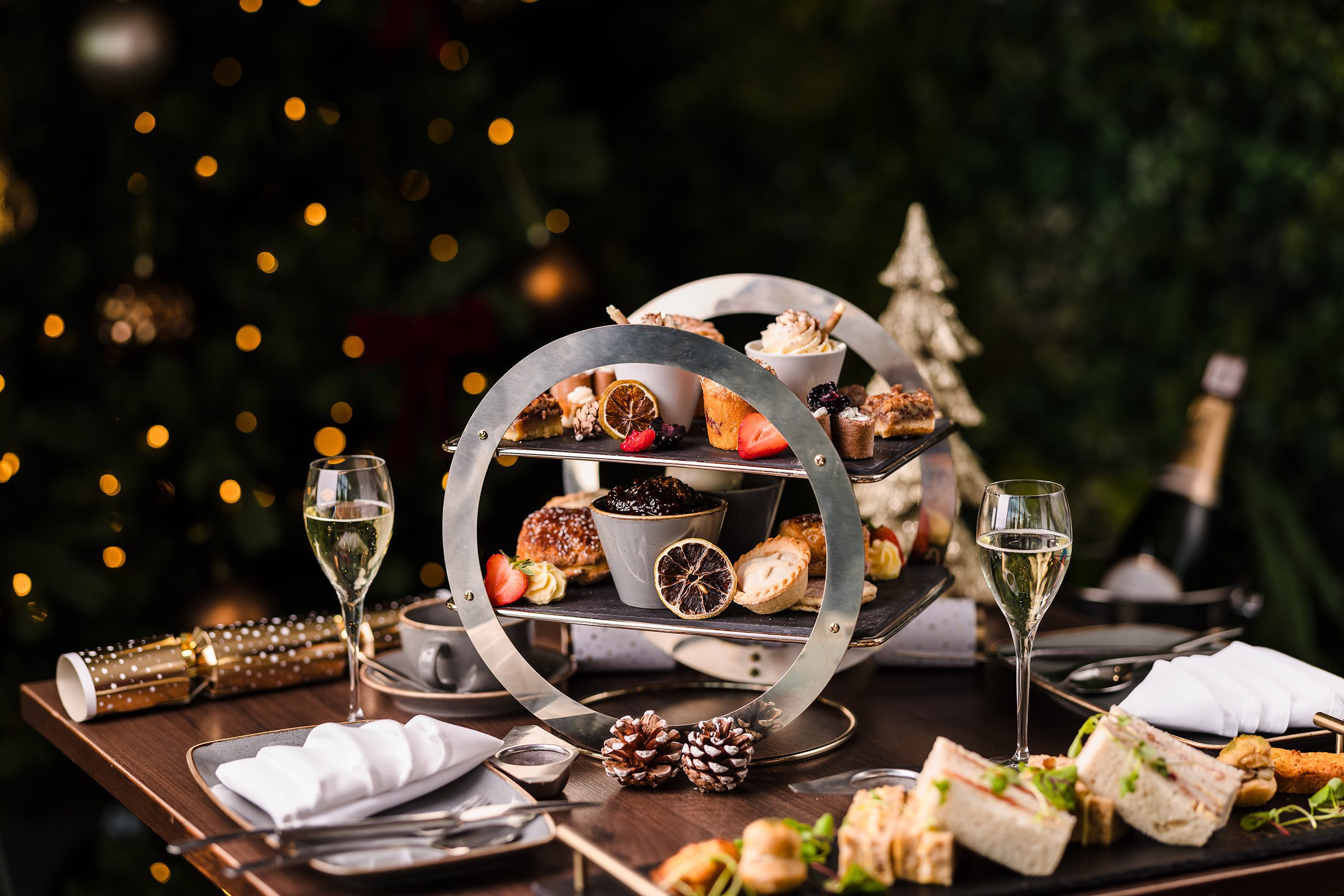 Christmas Eve afternoon tea with tiered desserts, sandwiches, champagne, and holiday decorations on the table.