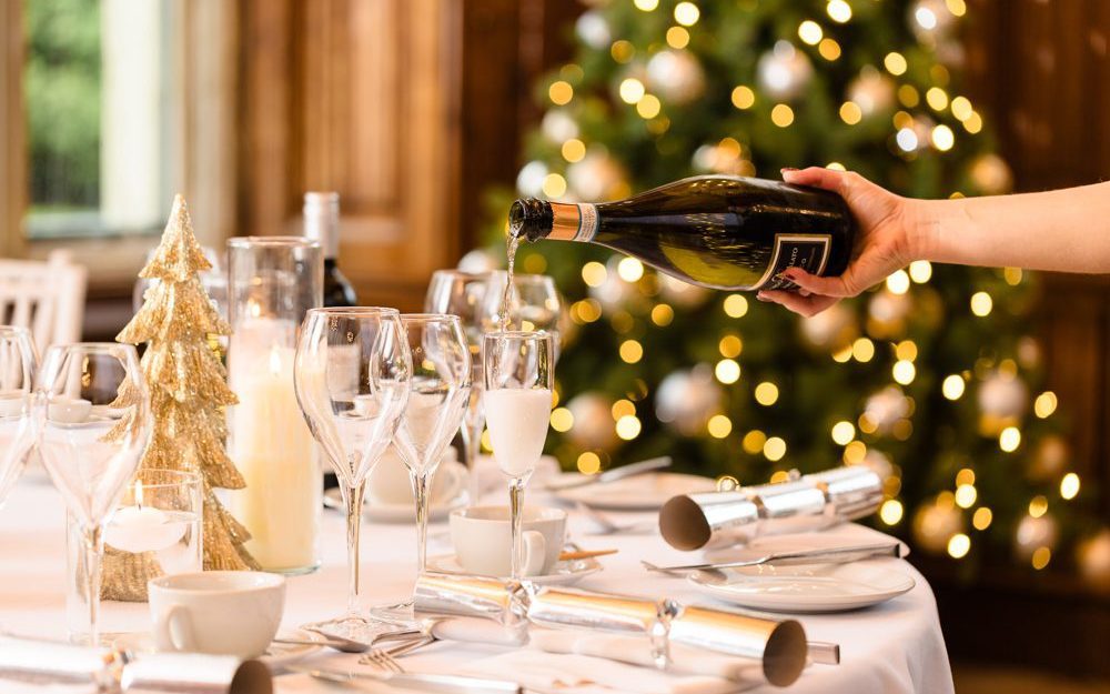 A hand pours champagne into a flute on a festive table, perfect for celebrating Christmas holiday 2026.