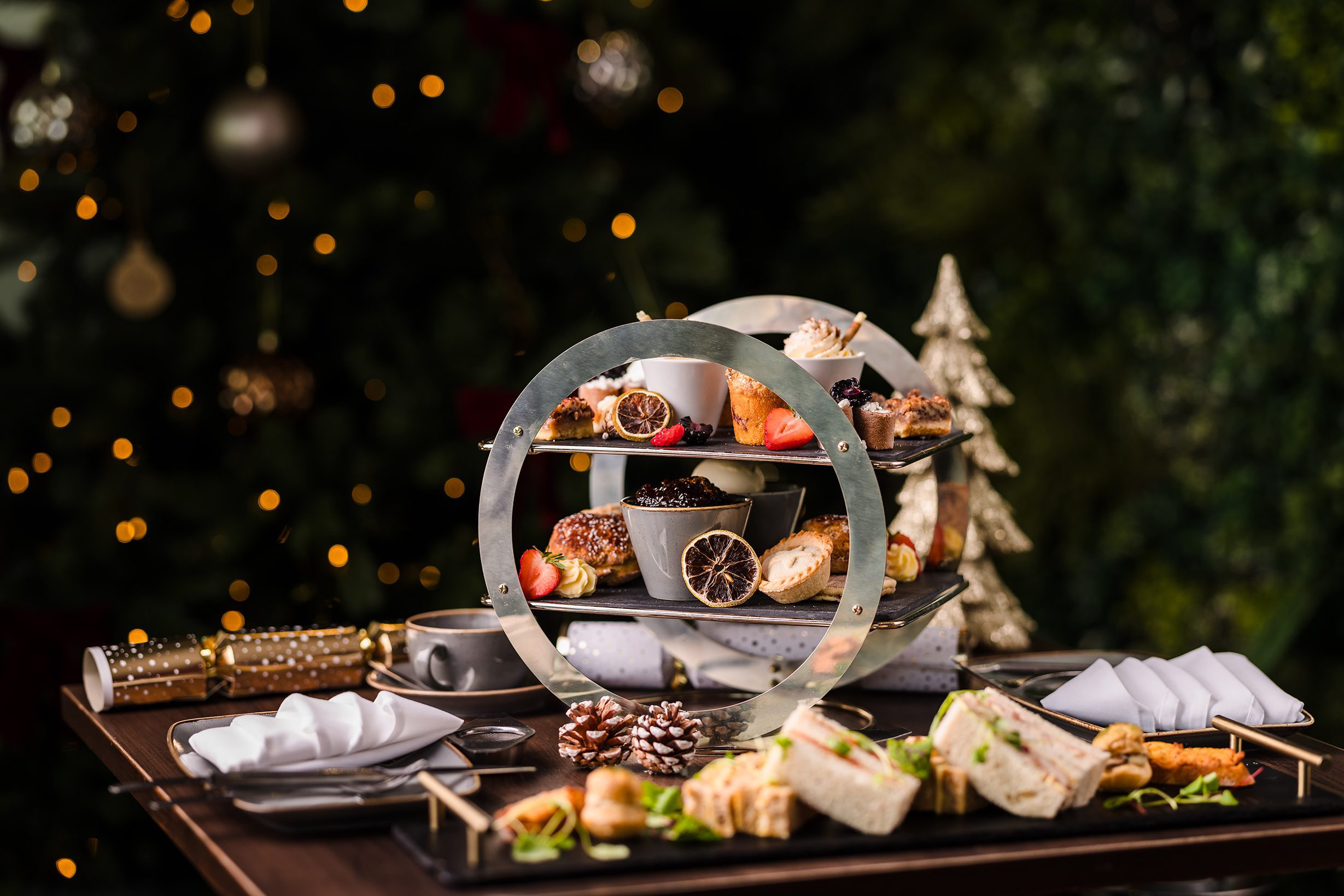 A tiered stand holding assorted pastries, sandwiches, and small desserts on a table set for afternoon tea.