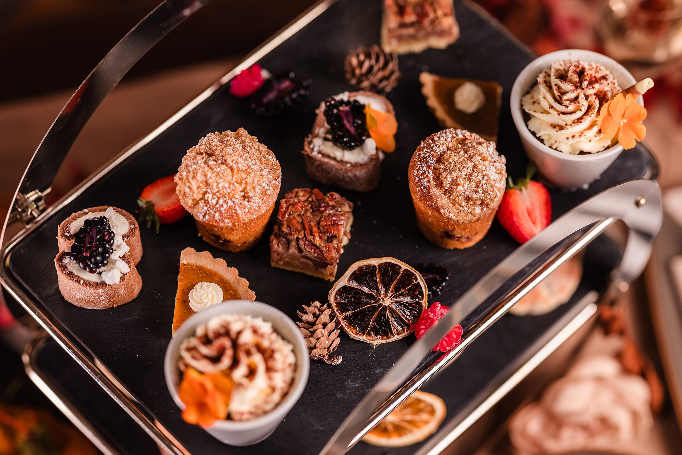 Assorted mini desserts perfect for afternoon tea, arranged on a stylish two-tiered black serving tray.