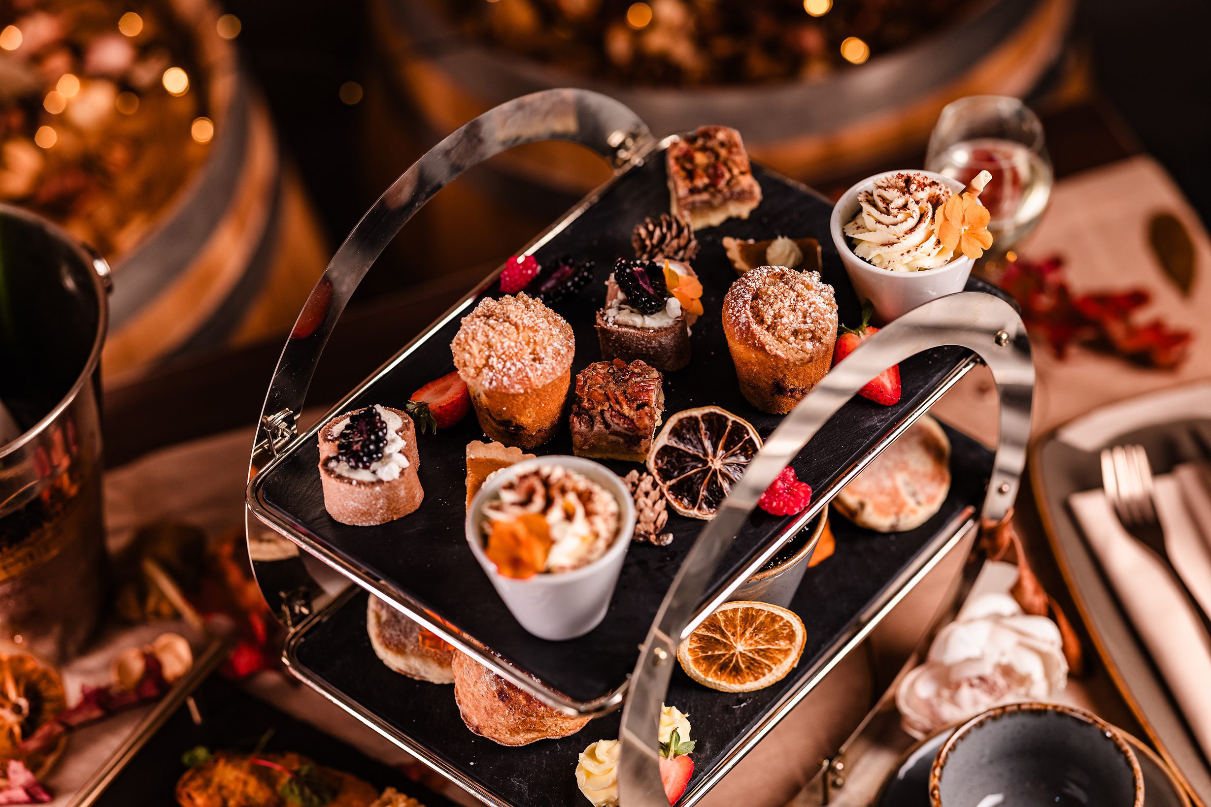 Indulge in mini desserts, cakes, and nuts on a two-tiered tray—perfect for hotel breaks South Wales style.
