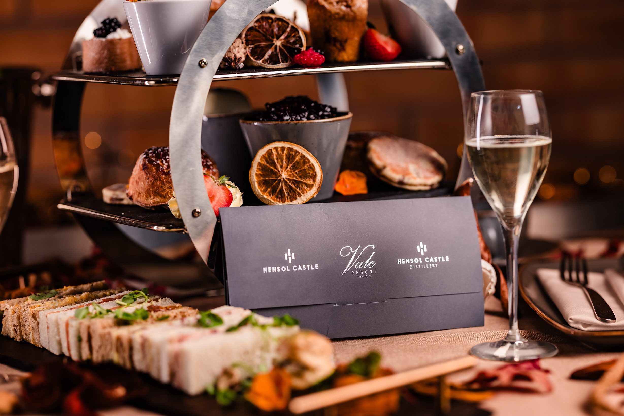 A tiered tray with assorted pastries, sandwiches, and white wine sets the scene for a perfect afternoon tea experience.